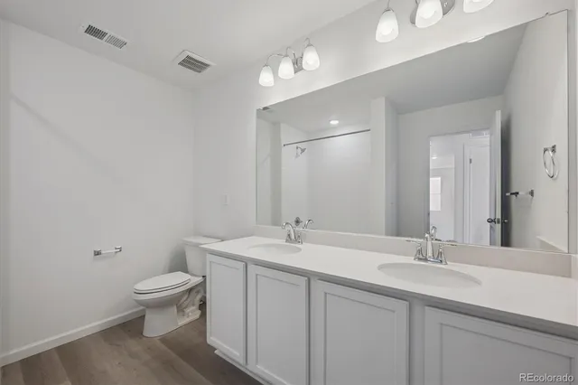 a bathroom with a sink a toilet a light fixture and a mirror