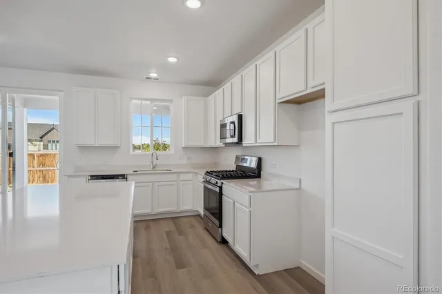 a kitchen with a sink a stove a refrigerator and white cabinets