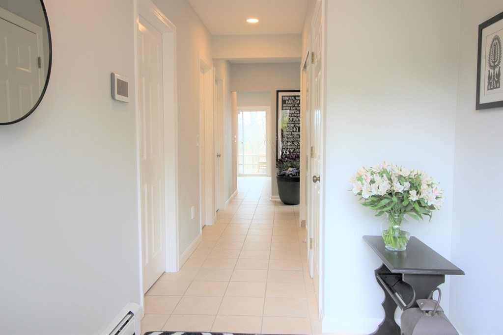 307 Ridgefield Circle, Unit D Clinton, MA 01510 - Photo 2 of 42 a hallway with a dining table & a potted plant