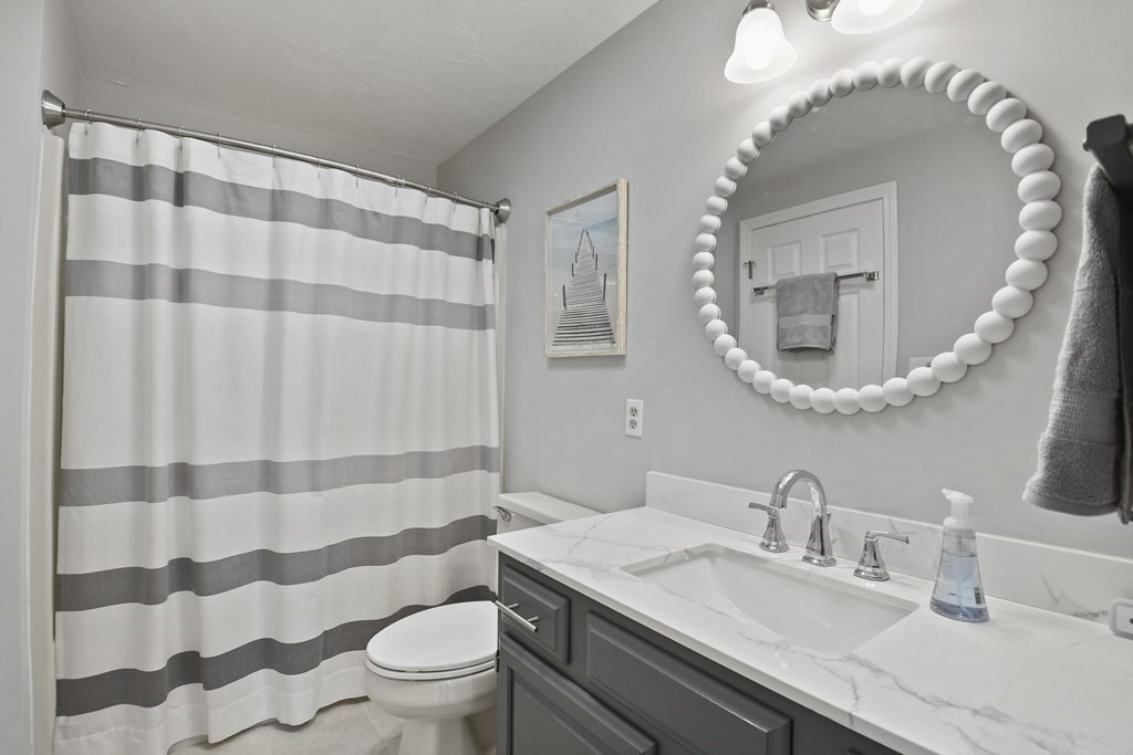 307 Ridgefield Circle, Unit D Clinton, MA 01510 - Photo 27 of 42 a bathroom with a sink a toilet a mirror and shower curtain