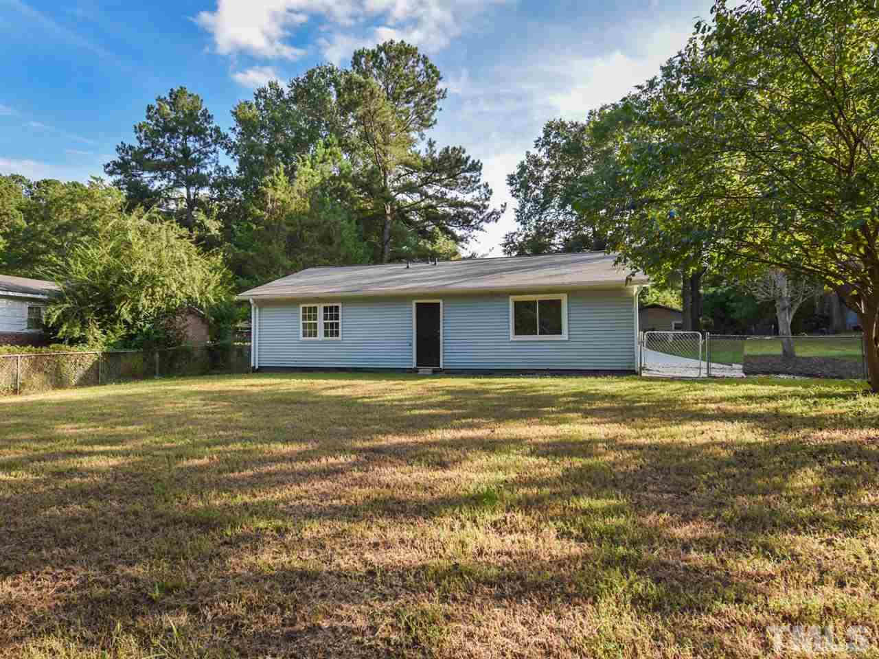 1221 Seabrook Road Raleigh, NC 27610 - Photo 16 of 16 a backyard of a house with large trees and a wooden bench