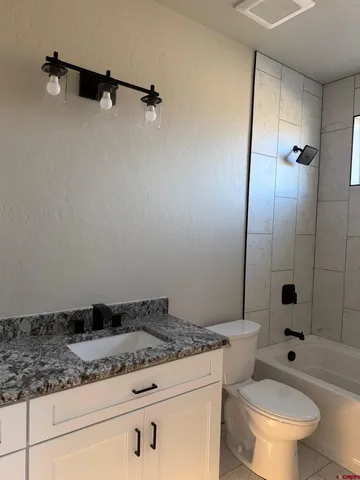 a bathroom with a granite countertop sink a toilet and shower