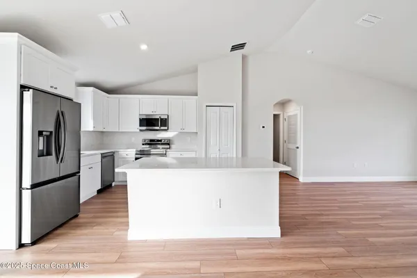 a kitchen with stainless steel appliances granite countertop a refrigerator a stove and a sink