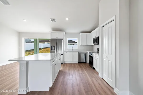 a kitchen with white cabinets and wooden floor
