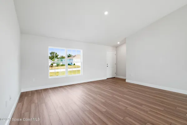 an empty room with wooden floor and window