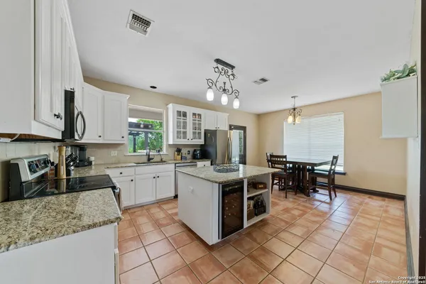 a kitchen with stainless steel appliances granite countertop a stove top oven a sink dishwasher a dining table and chairs with wooden floor