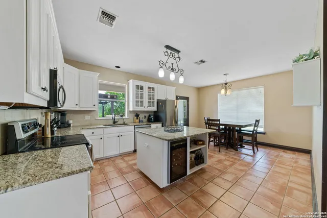 a kitchen with stainless steel appliances granite countertop a stove top oven a sink dishwasher a dining table and chairs with wooden floor