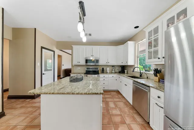 a large kitchen with granite countertop a sink counter top space appliances and cabinets
