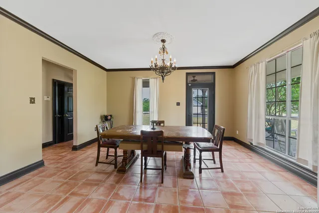 a dining room with wooden floor a chandelier a wooden table and chairs
