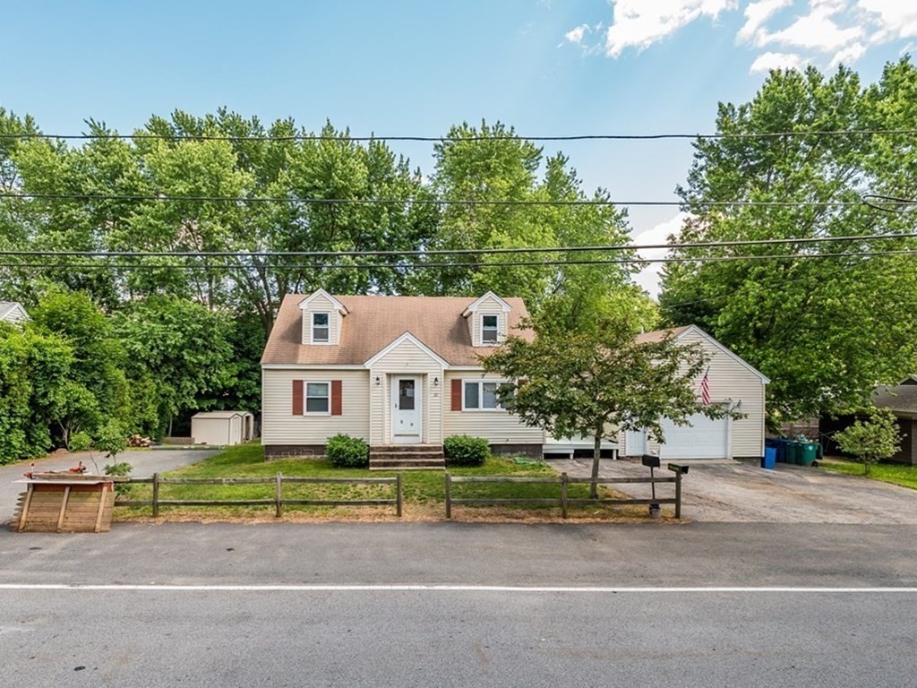 a front view of a house with a garden and trees