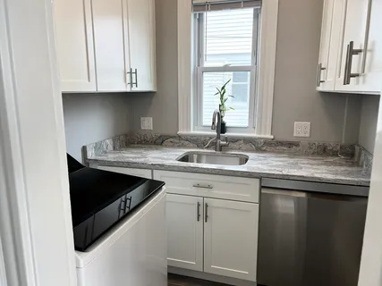 a kitchen with granite countertop white cabinets and a sink