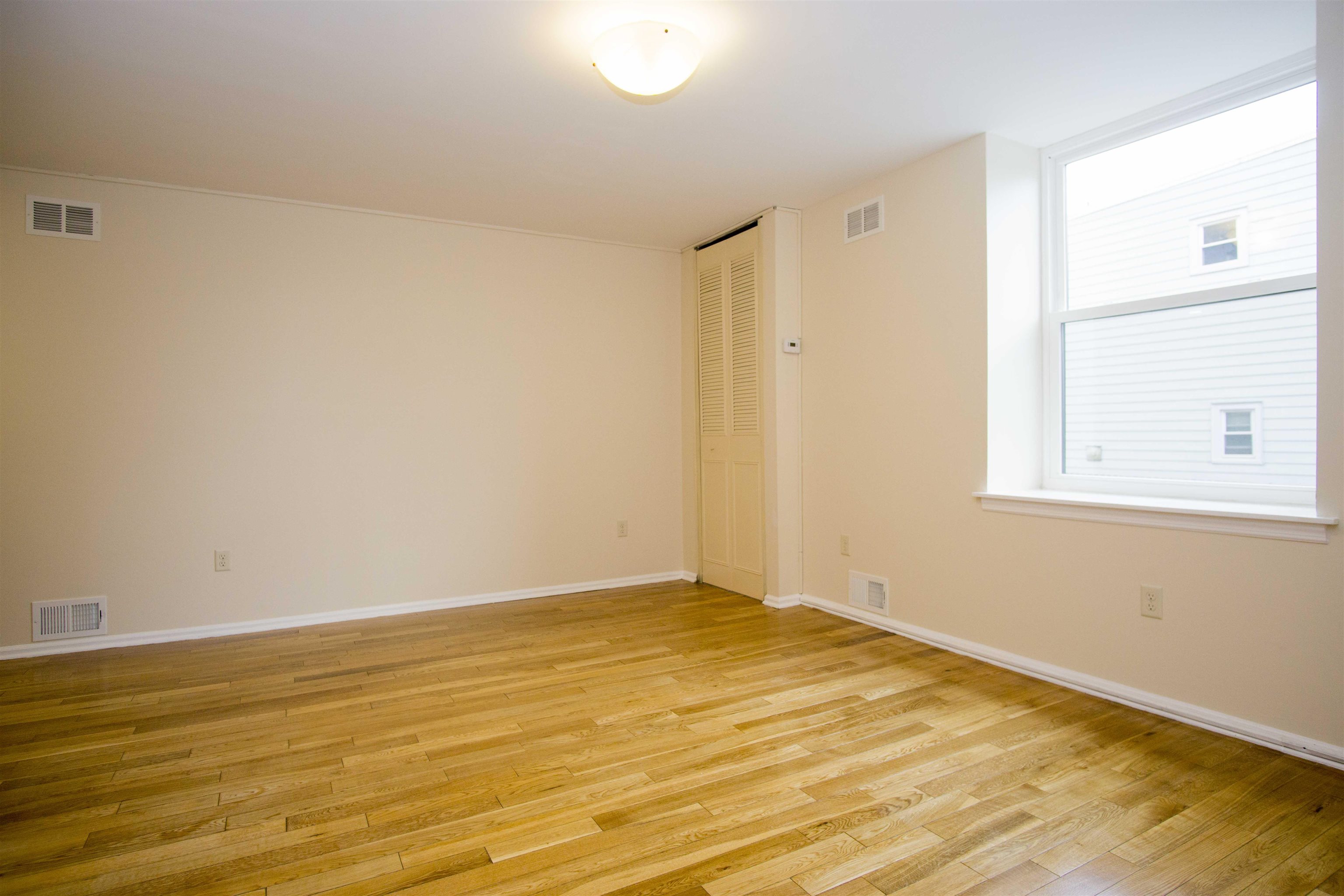 200 Central Avenue, Unit B5 Jersey City, NJ 07307 - Photo 4 of 12 a view of an empty room with wooden floor and a window