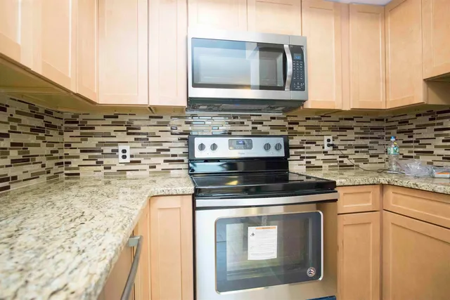 a kitchen with stainless steel appliances granite countertop a stove a sink and a microwave