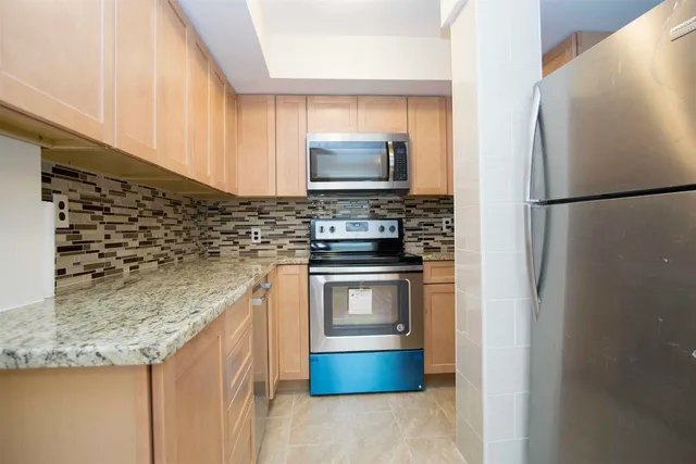 a kitchen with stainless steel appliances granite countertop a refrigerator and a stove top oven