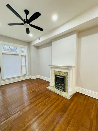 an empty room with wooden floor a ceiling fan and a fireplace