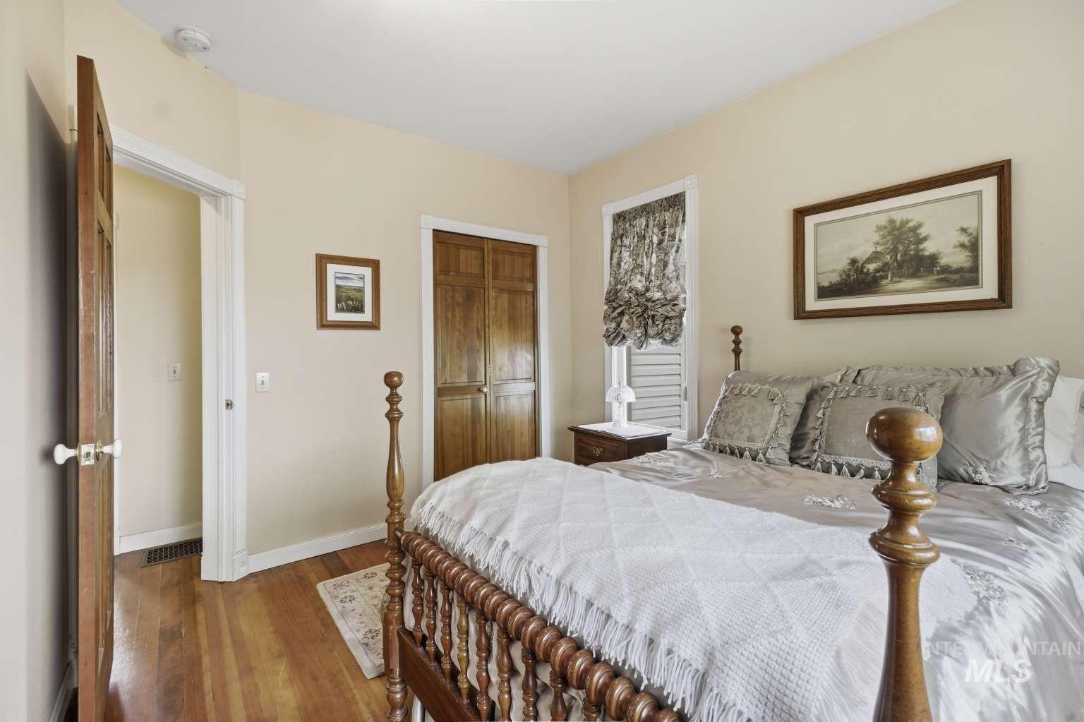 901 Main Street Kendrick, ID 83537 - Photo 23 of 50 Bedroom featuring light-colored walls, wood-finish flooring, a built-in closet with bi-fold wood doors, and a window with interior shutters