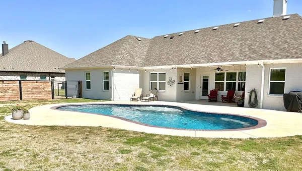 a view of house with swimming pool and sitting area