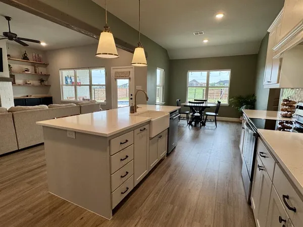 a kitchen with stainless steel appliances granite countertop a stove a refrigerator a kitchen island with wooden cabinets dining table and chairs