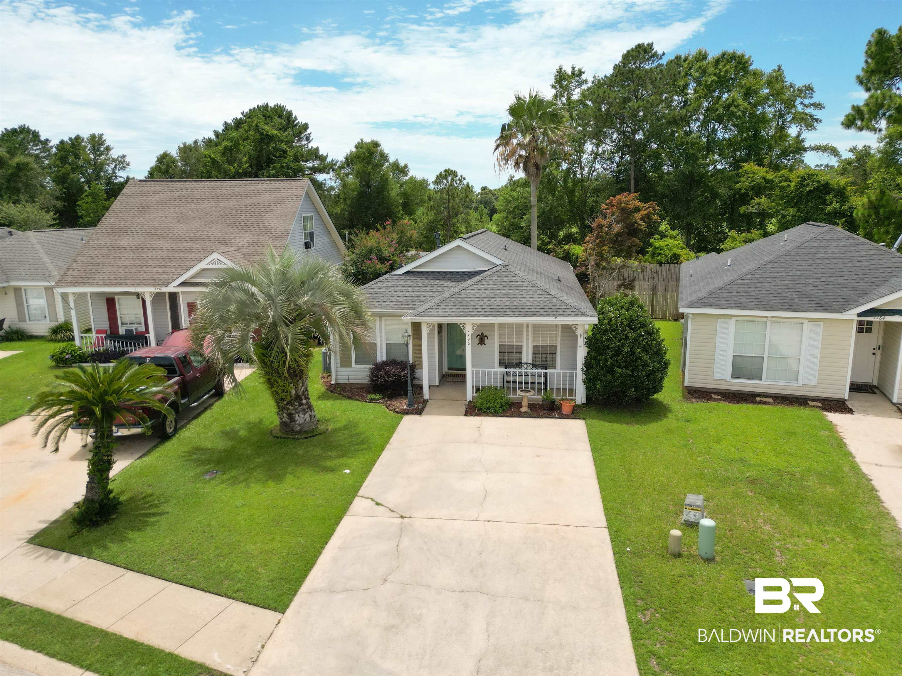 7790 Audubon Drive Foley, AL 36535 - Photo 2 of 39 Single-story residence featuring a covered front porch with white railings, a light gray exterior, and a dark gray shingle roof