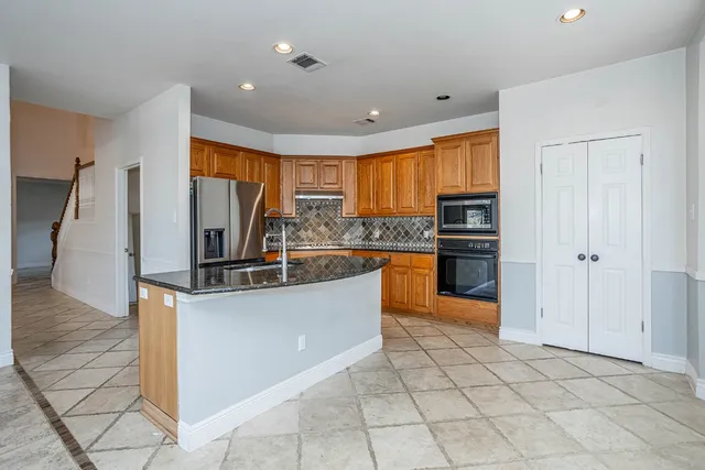 a kitchen with granite countertop a sink and a refrigerator