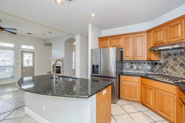 a kitchen with stainless steel appliances granite countertop a stove a sink and a granite counter tops with white cabinets next to a window