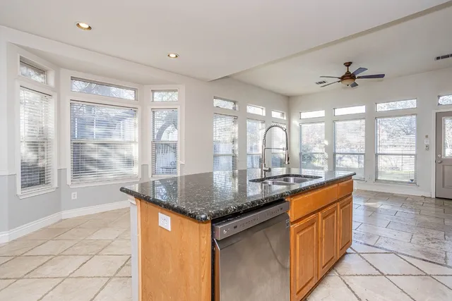 a kitchen with stainless steel appliances granite countertop a sink a counter space and a window