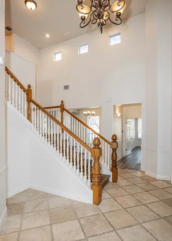 a view of staircase with lots of frames on wall and a chandelier