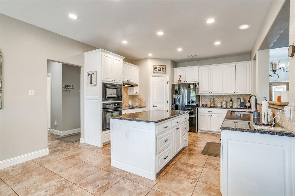 1249 Handkerchief Way Fort Worth, TX 76052 - Photo 31 of 40 a kitchen with stainless steel appliances kitchen island granite countertop a refrigerator and a stove top oven