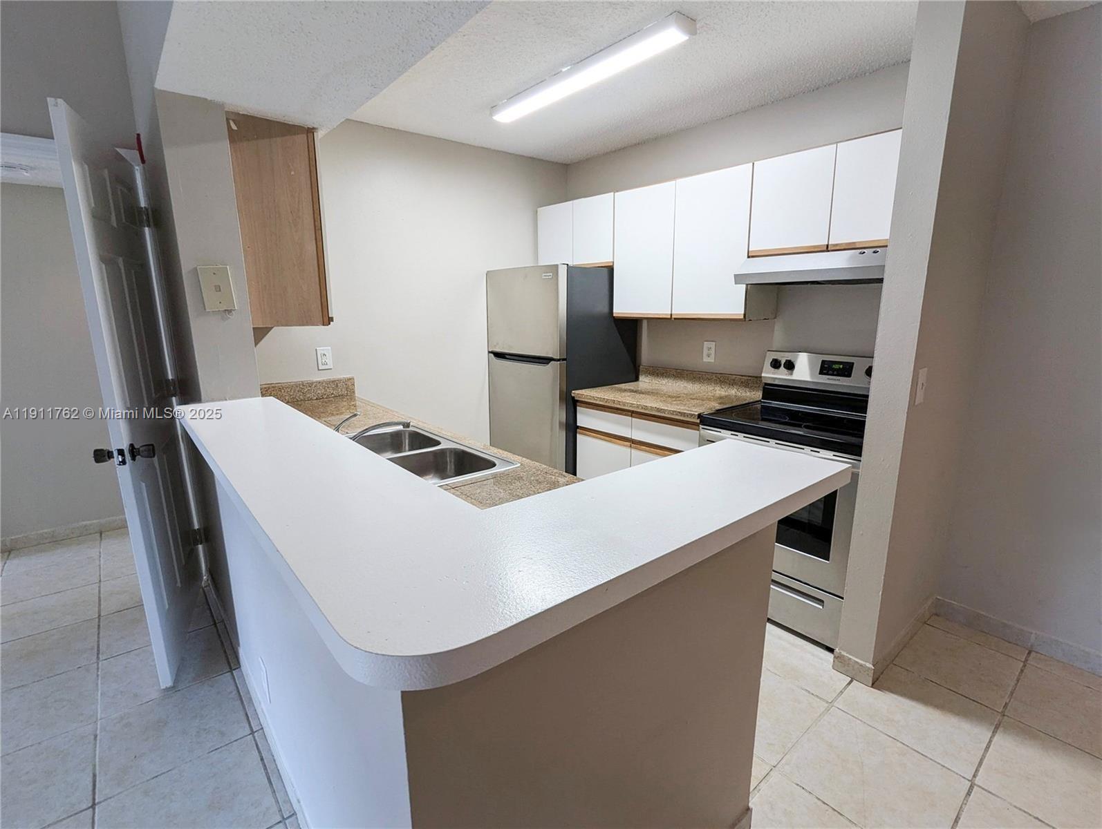 4015 West McNab Road, Unit D308 Pompano Beach, FL 33069 - Photo 2 of 17 a kitchen with stainless steel appliances a stove refrigerator sink and cabinets