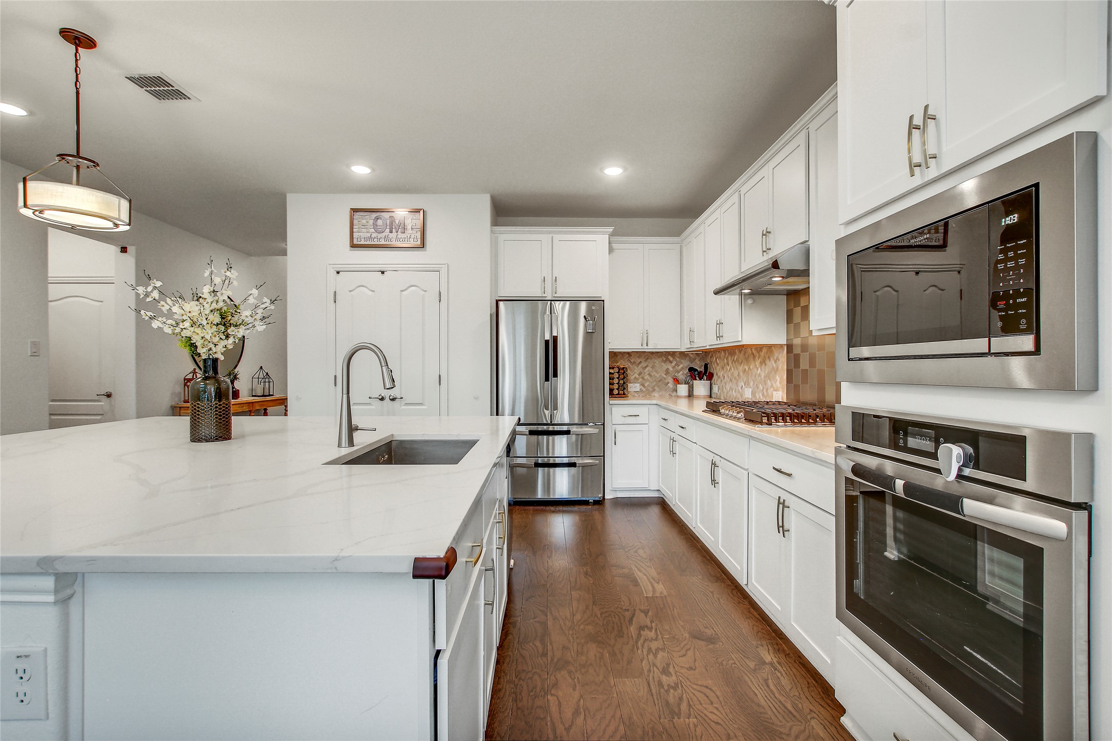 104 Millbend Road Georgetown, TX 78633 - Photo 13 of 40 White cabinetry, rich wood floors, and a bright kitchen island create an inviting culinary space.