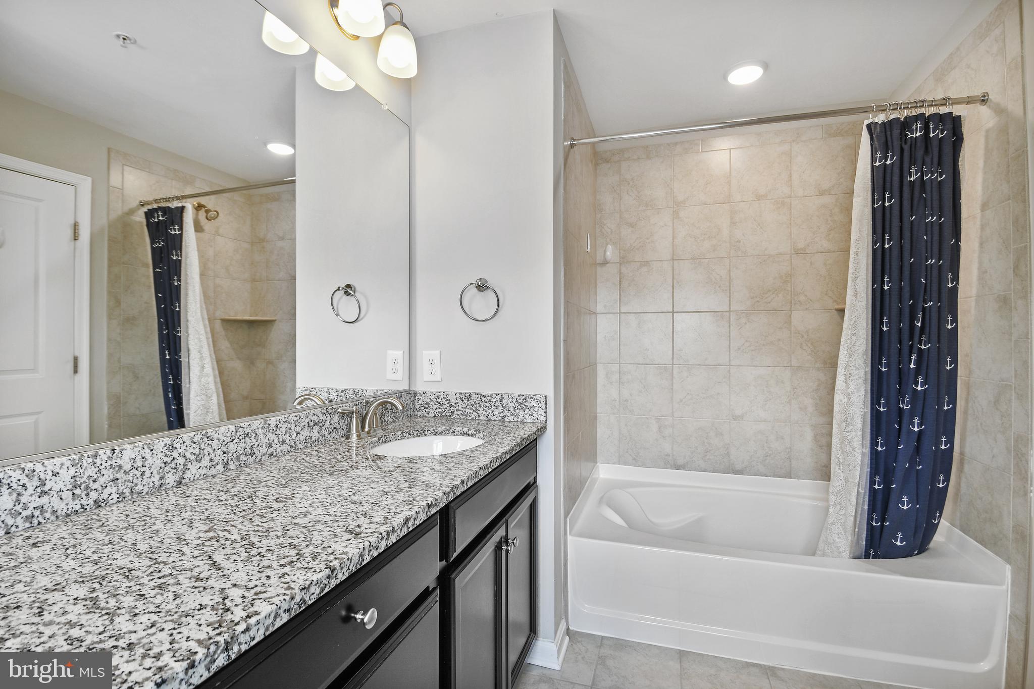 4648 Cambria Road Frederick, MD 21703 - Photo 14 of 22 a bathroom with a granite countertop sink a mirror and a bathtub