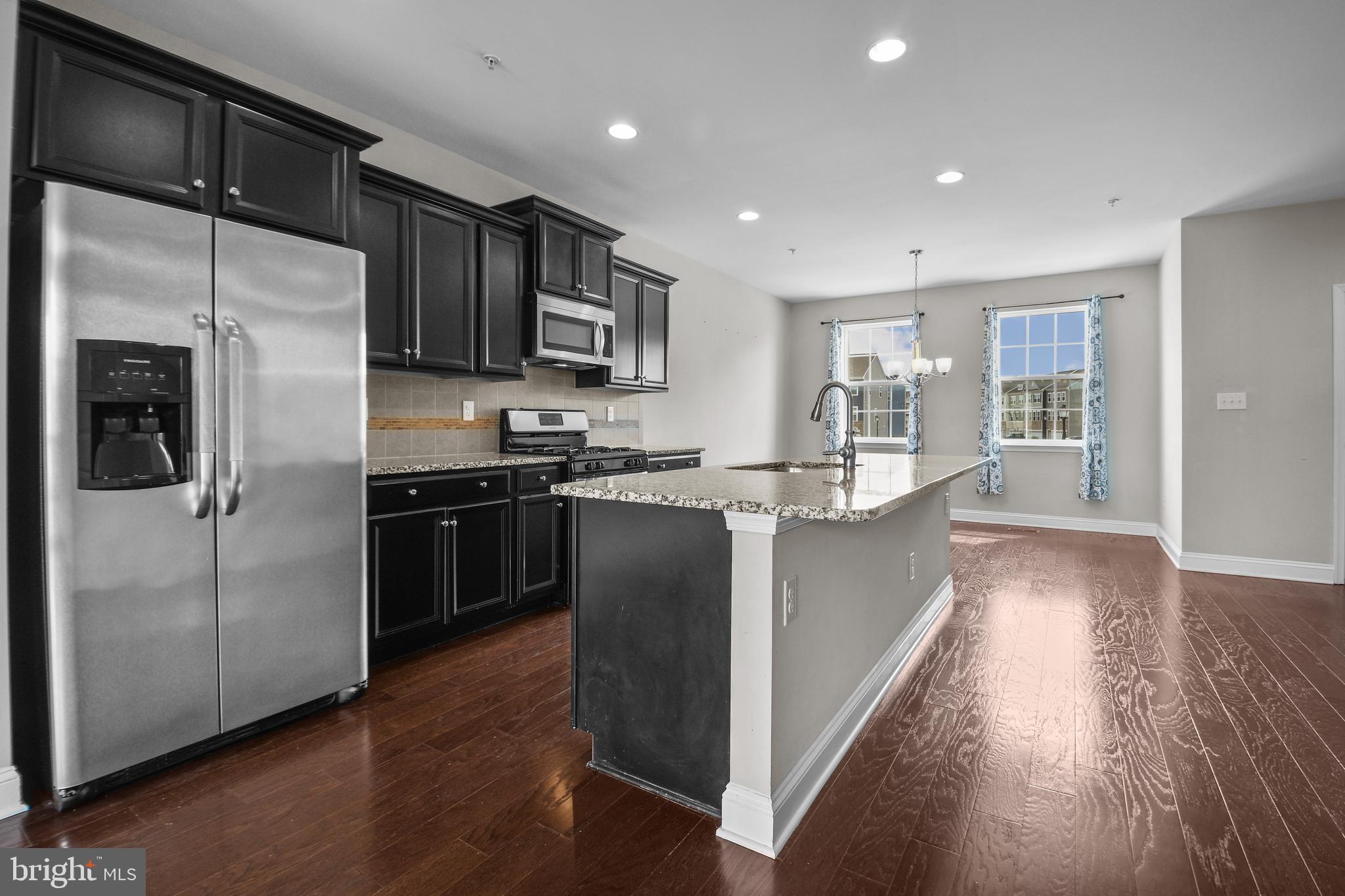 4648 Cambria Road Frederick, MD 21703 - Photo 2 of 22 a kitchen with kitchen island granite countertop stainless steel appliances and wooden cabinets