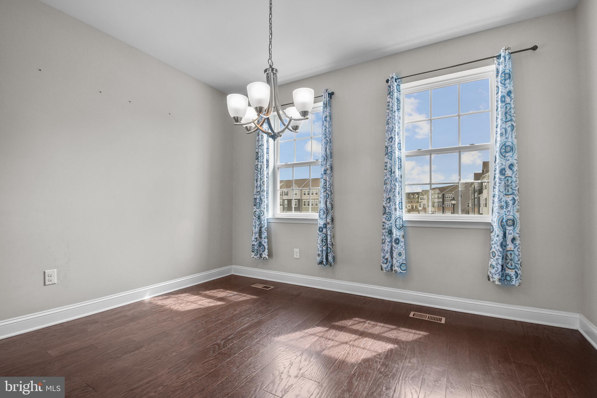 4648 Cambria Road Frederick, MD 21703 - Photo 6 of 22 an empty room with wooden floor chandelier and windows