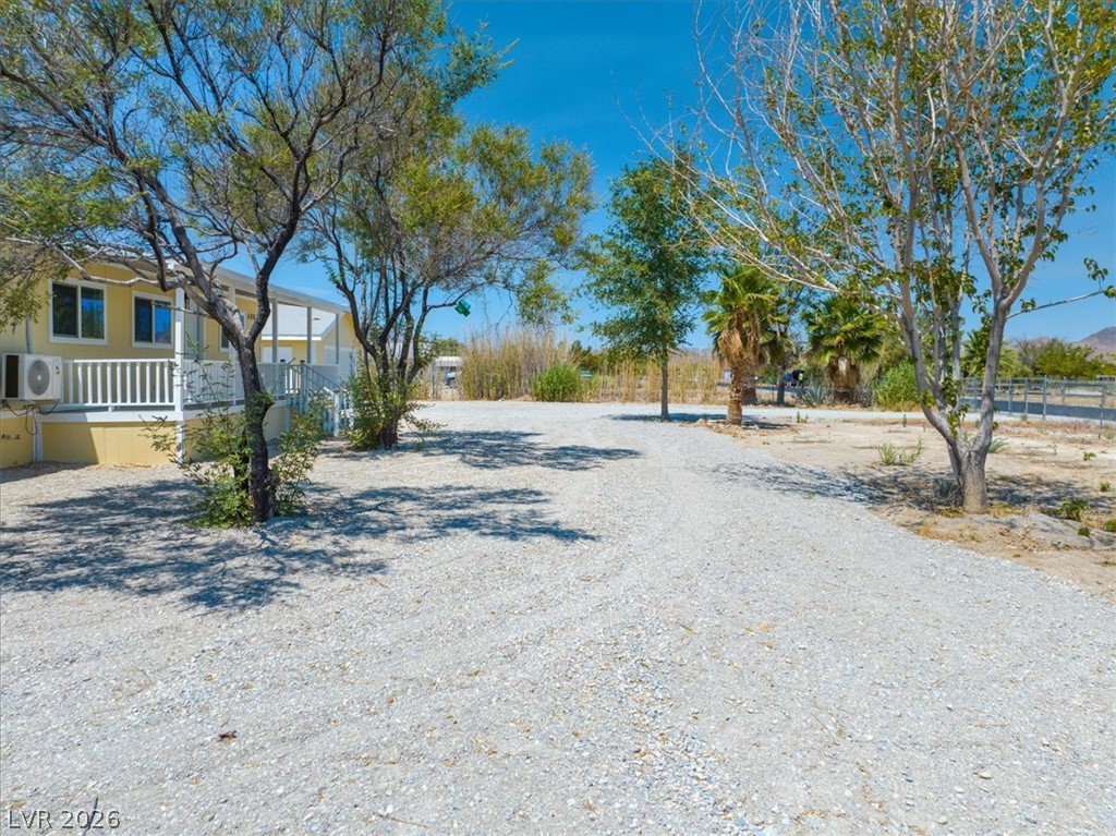 4081 Retread Road Pahrump, NV 89048 - Photo 76 of 98 A long gravel driveway leads to a welcoming residence with a white porch railing.