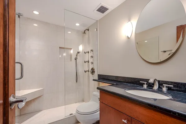 a bathroom with a granite countertop sink mirror vanity and toilet
