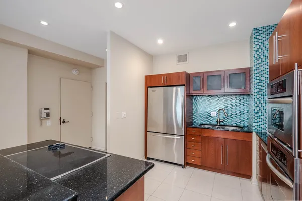a kitchen with stainless steel appliances granite countertop a refrigerator a stove and a sink