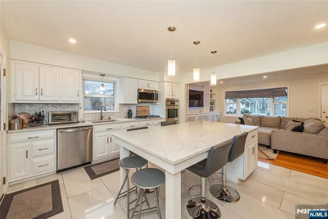 a large white kitchen with a stove a sink a dining table and chairs