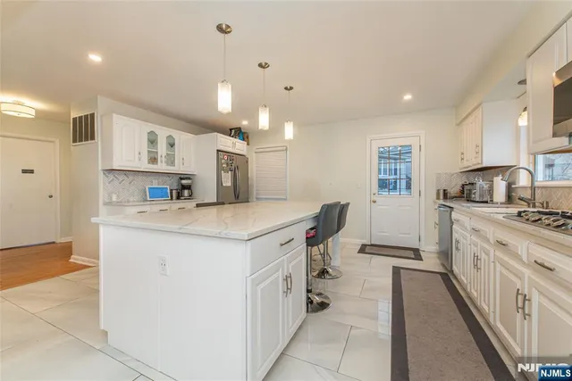 a kitchen with stainless steel appliances granite countertop a sink a stove and a refrigerator