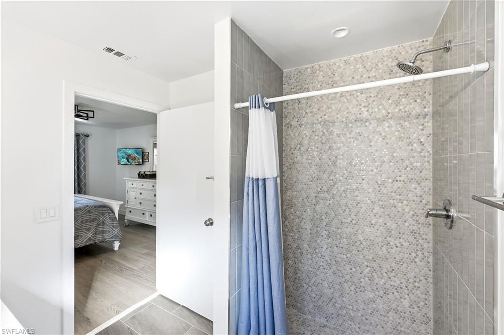 7707 Jewel Lane, Unit 201 Naples, FL 34109 - Photo 26 of 31 Ensuite bathroom featuring a stall shower and wood finished floors