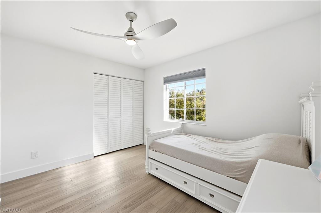 7707 Jewel Lane, Unit 201 Naples, FL 34109 - Photo 6 of 31 Bedroom featuring light wood finished floors, a ceiling fan, and a closet