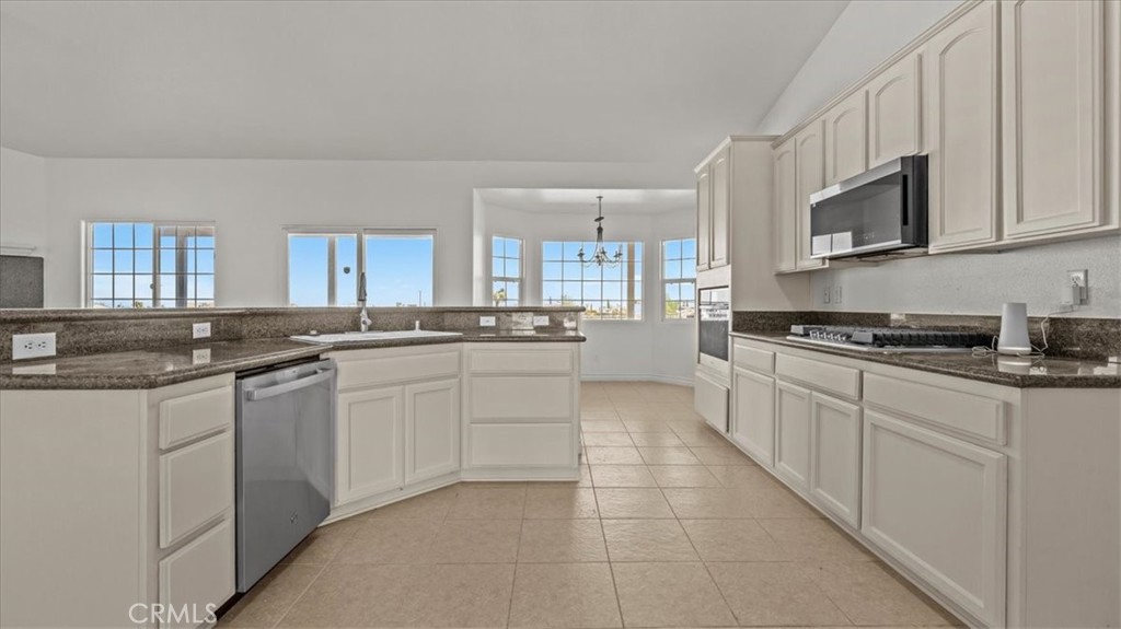 7536 Sunset Road Phelan, CA 92371 - Photo 8 of 40 a large white kitchen with stainless steel appliances granite countertop a sink and dishwasher a stove top oven with white cabinets