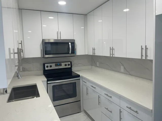 a kitchen with granite countertop white cabinets and stainless steel appliances