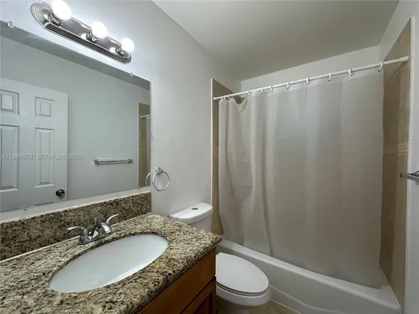 a bathroom with a granite countertop bathtub shower sink and toilet