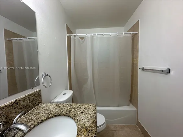 a bathroom with a granite countertop sink toilet and a mirror