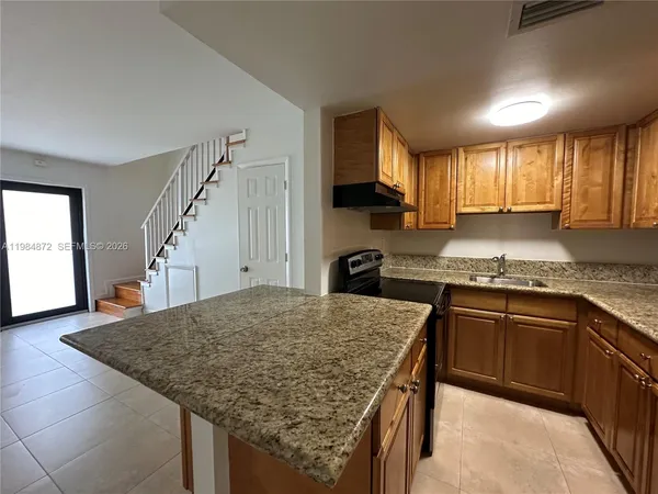 a kitchen with granite countertop kitchen island stainless steel appliances a sink stove and cabinets