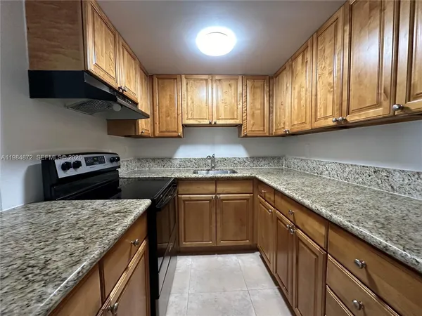 a kitchen with granite countertop stainless steel appliances a sink stove top oven and cabinets