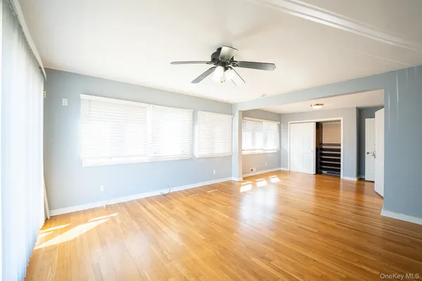 a view of an empty room with window and wooden floor