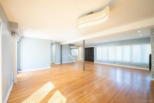a view of an empty room with window and wooden floor
