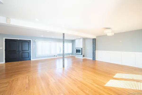 a view of an empty room with window and wooden floor