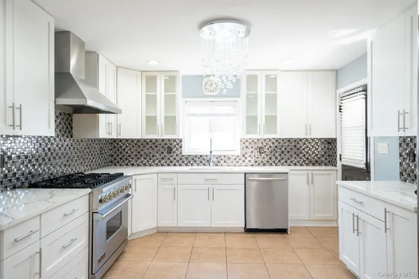 a kitchen with stainless steel appliances granite countertop white cabinets a window and a sink